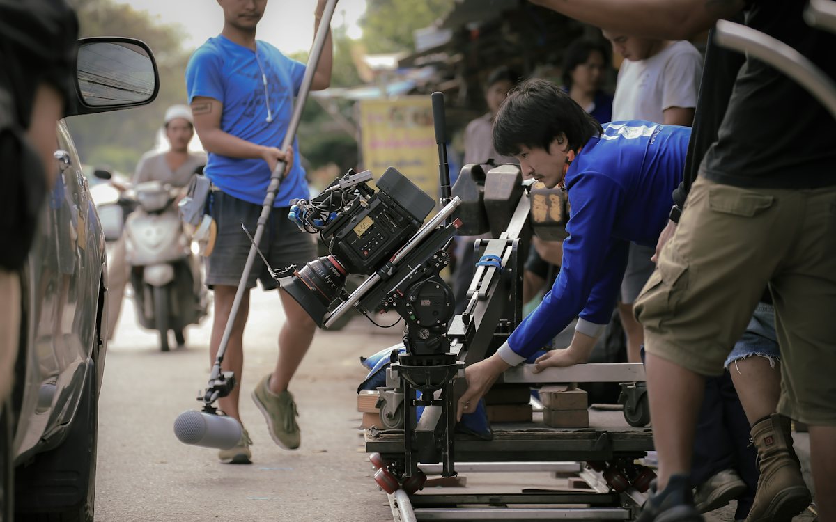 Crew moving a camera dolly and grip equipment along a street
